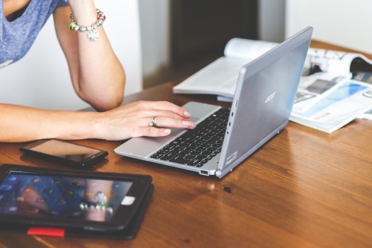 woman-working-on-laptop-with-magazines-on-table